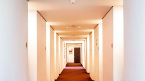 A long, narrow hotel corridor with carpeted floors and white walls. - Best Western Plus Hotel San Diego (Medellín)