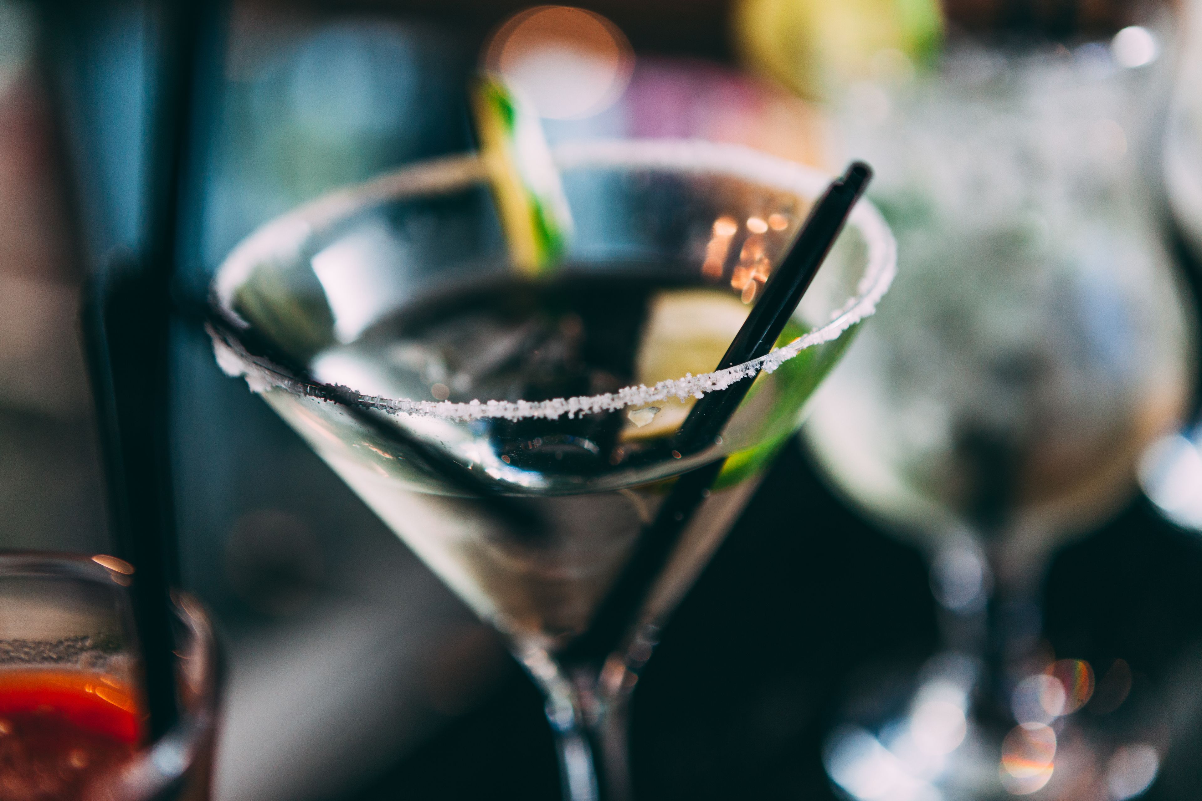A close-up of a martini glass with a salted rim and a straw.