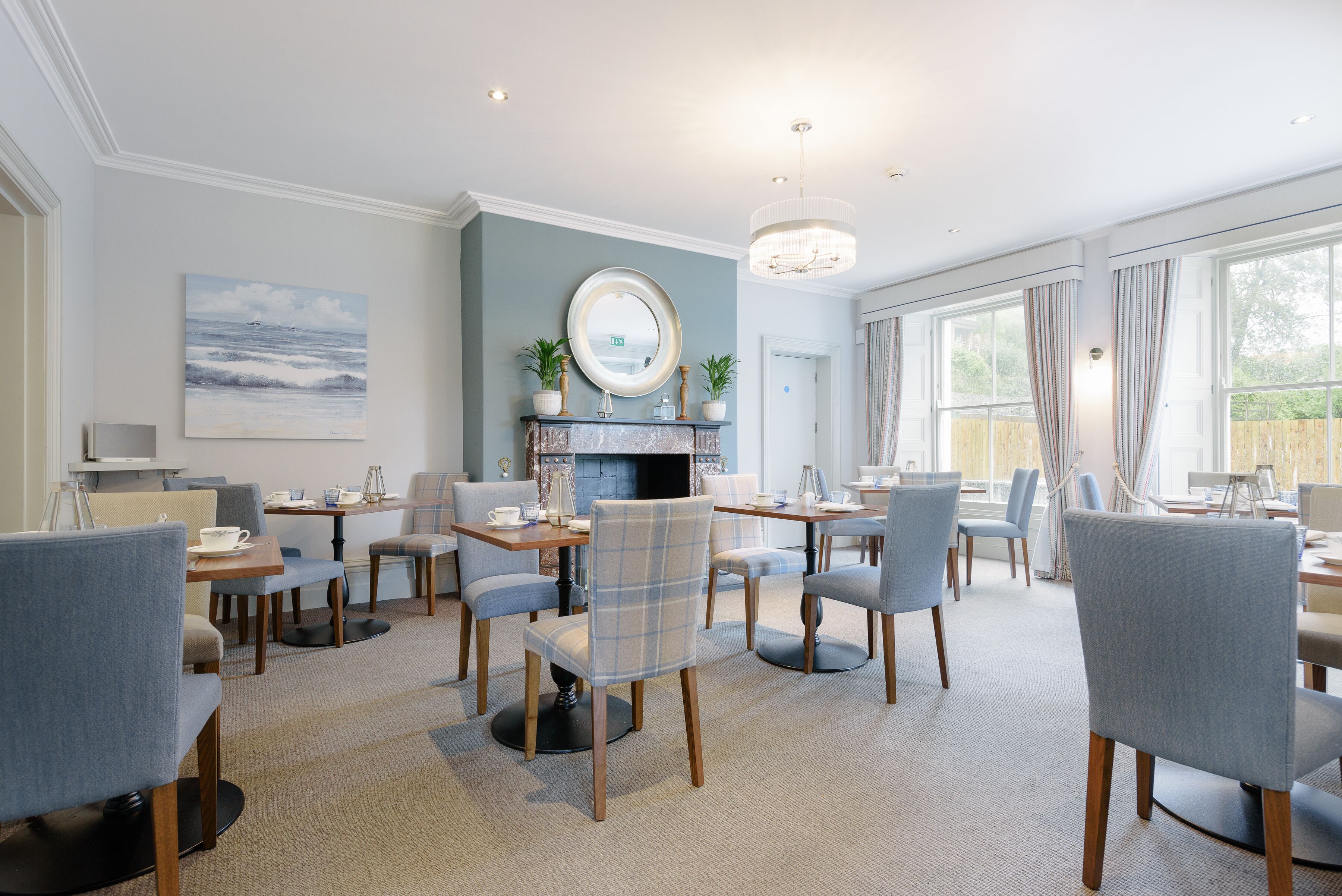 A modern dining area with a fireplace, comfortable seating, and large windows.