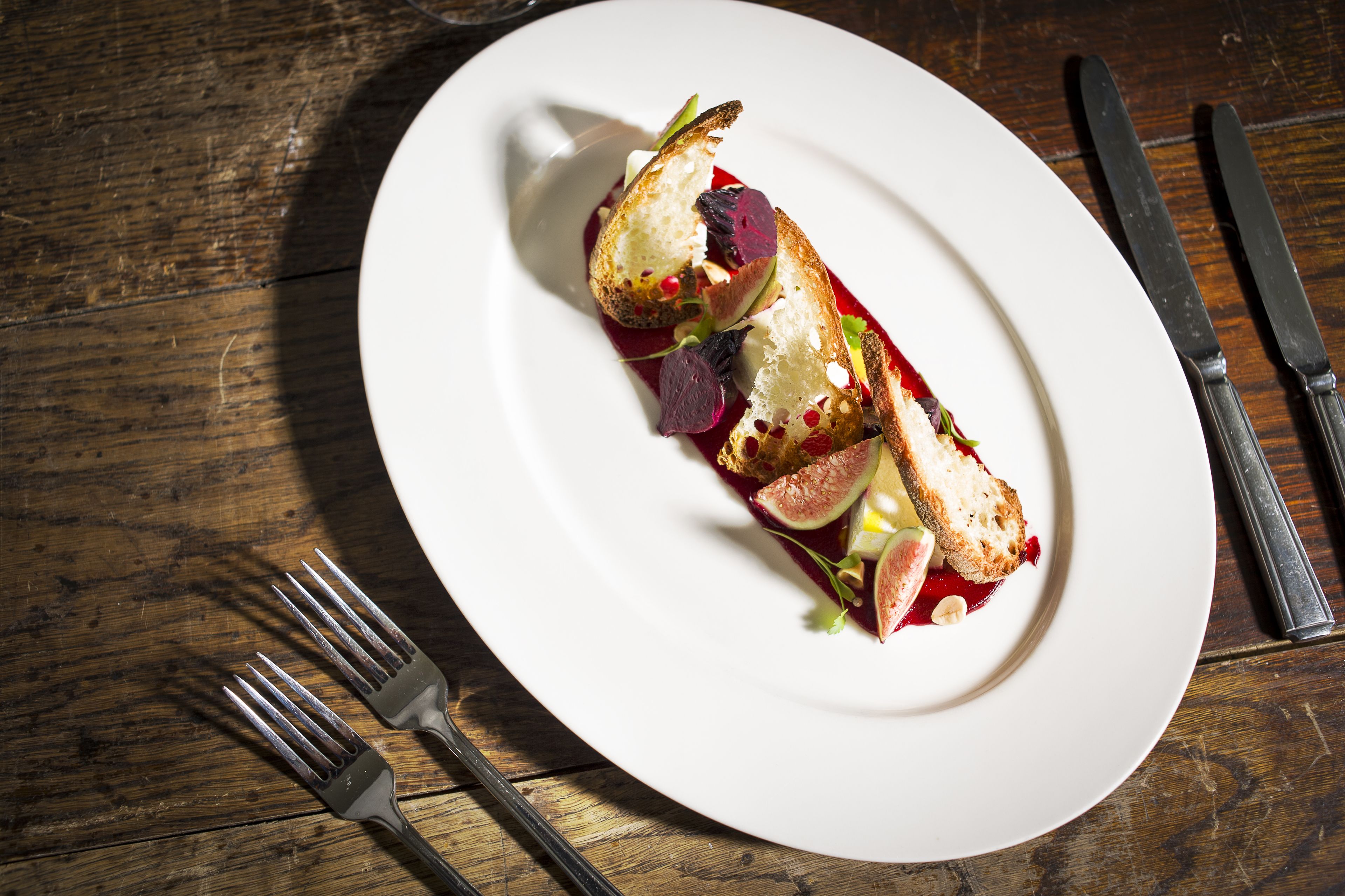 A white plate with a dish on a wooden table.