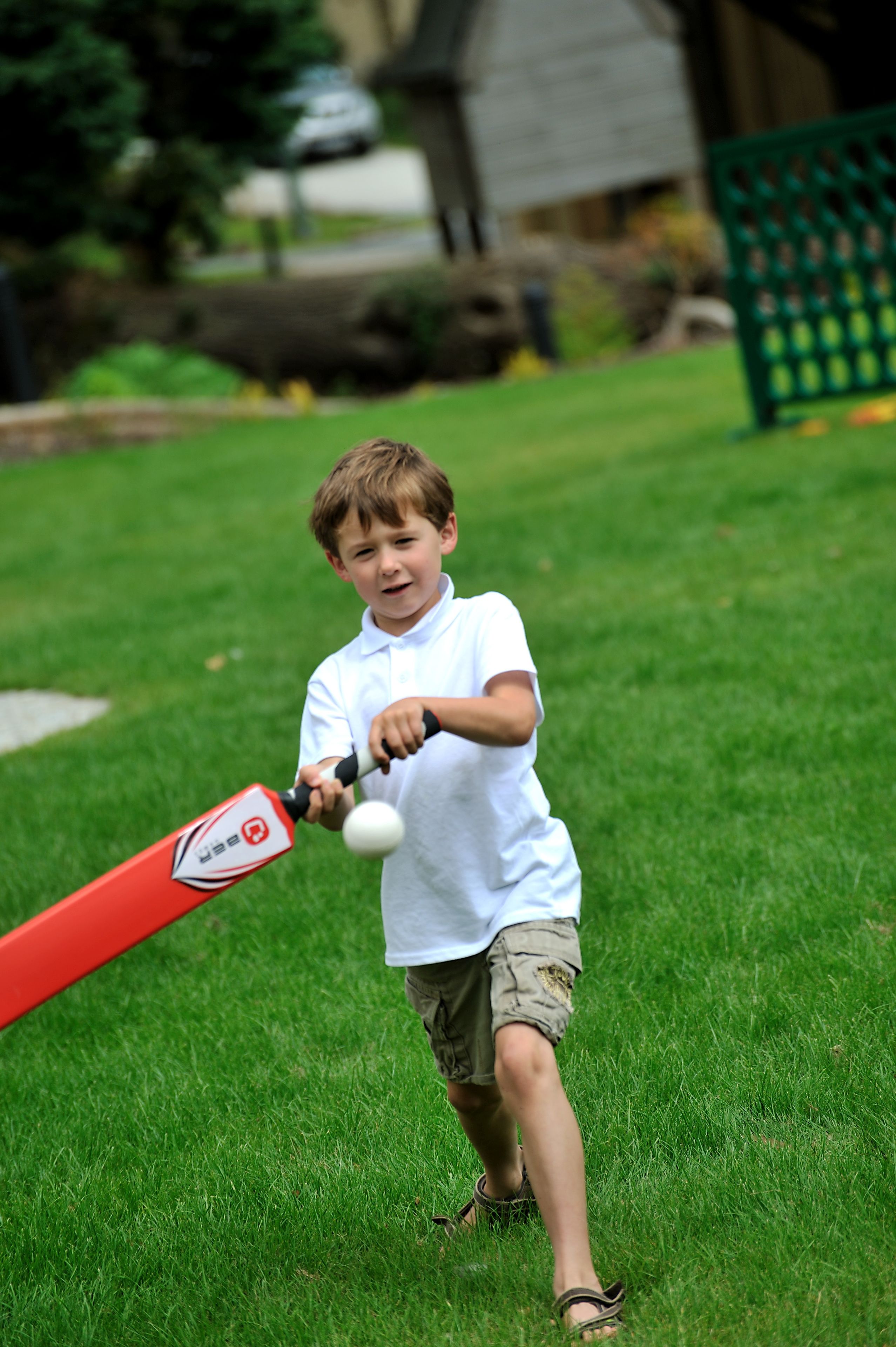 Et barn leger med et baseballbat på en græsplæne.