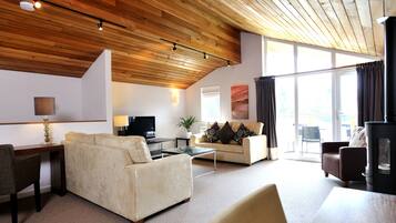 A modern living room with a high ceiling, a sofa, a TV, and a fireplace.