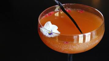 A cocktail in a glass with a flower garnish.
