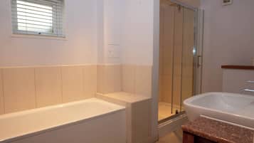 A bathroom with a bathtub, a shower enclosure, and a sink.