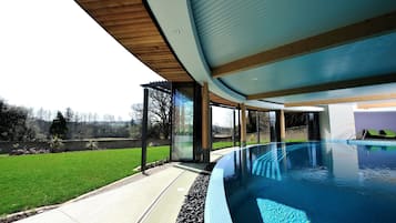 Relax by the pool surrounded by lush greenery and a serene landscape.