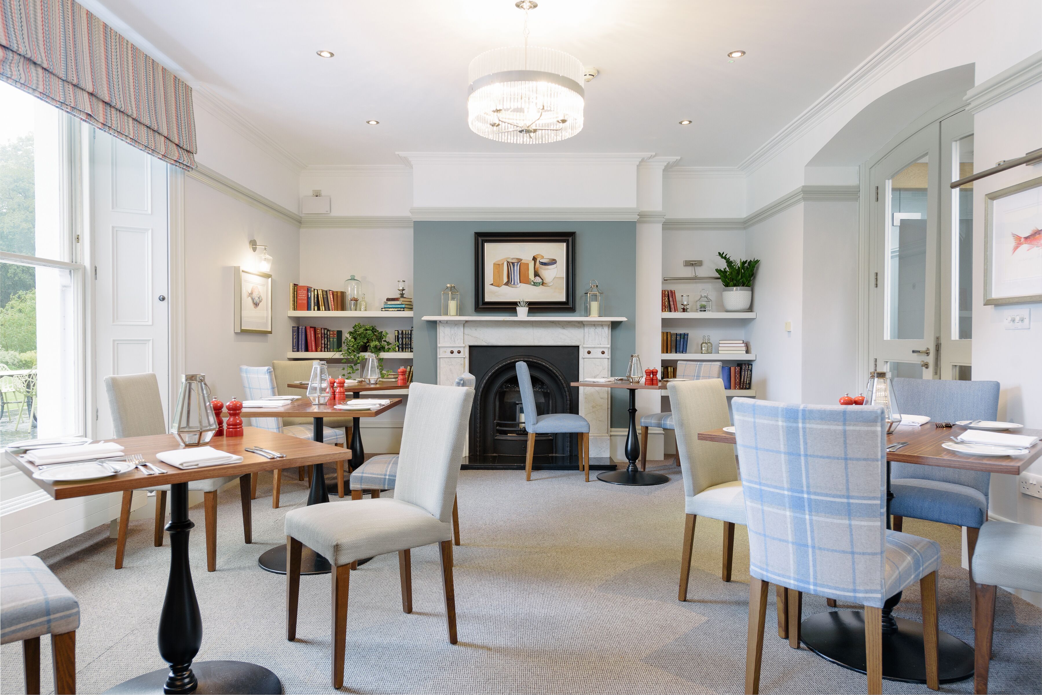 A dining area with a fireplace, bookshelves, and a chandelier.