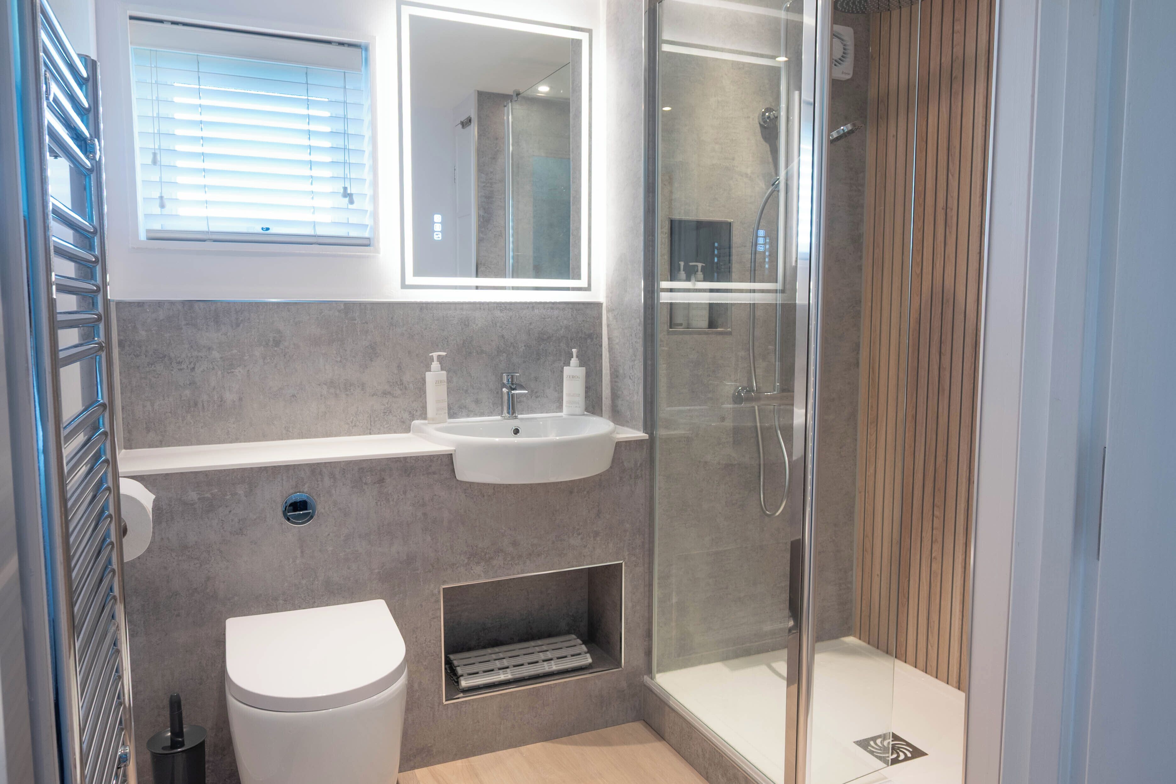 A modern bathroom with a glass-enclosed shower, a white sink, and a toilet.