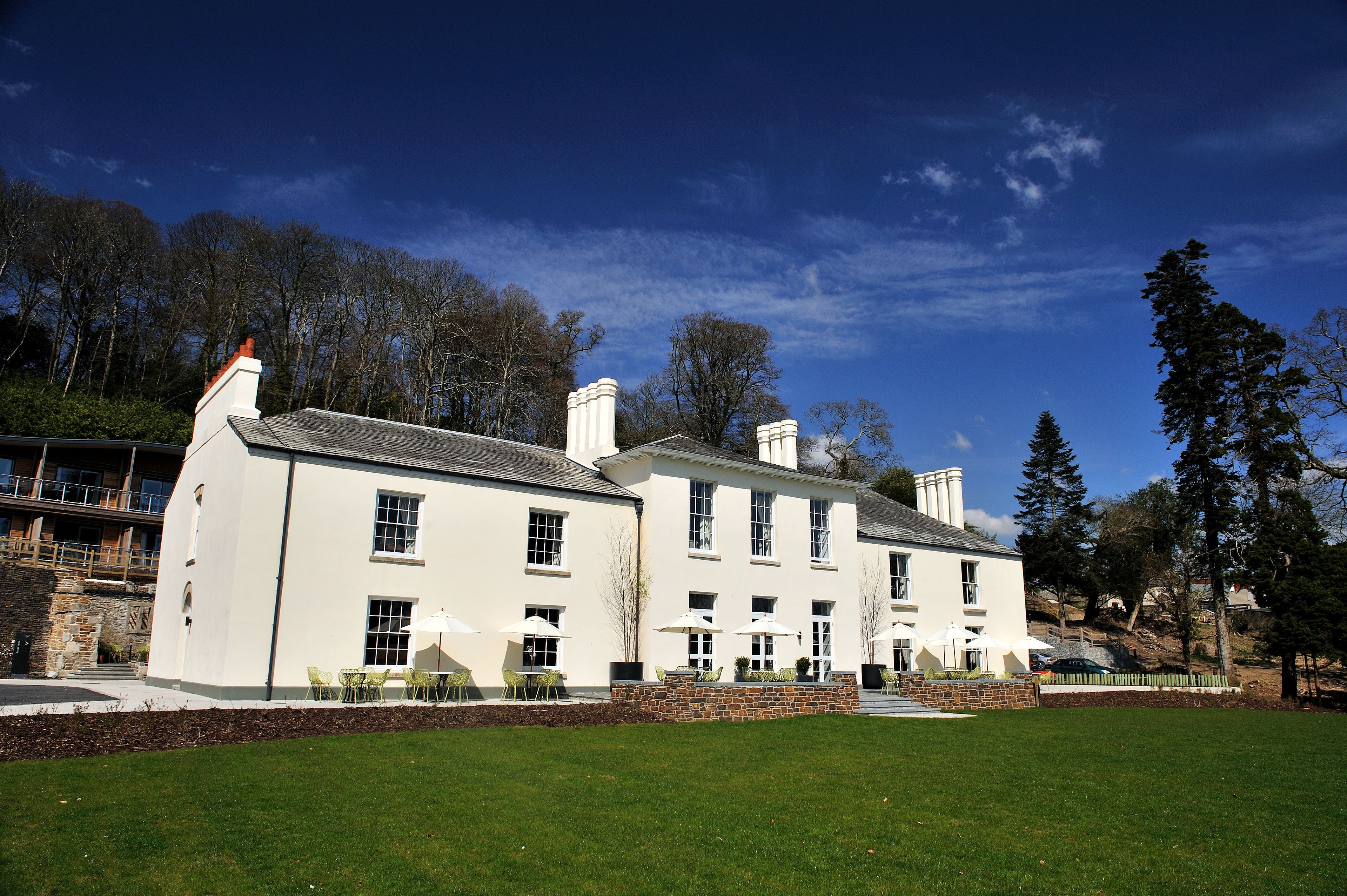 A large, white building with multiple chimneys, a stone facade, and a well-maintained lawn.