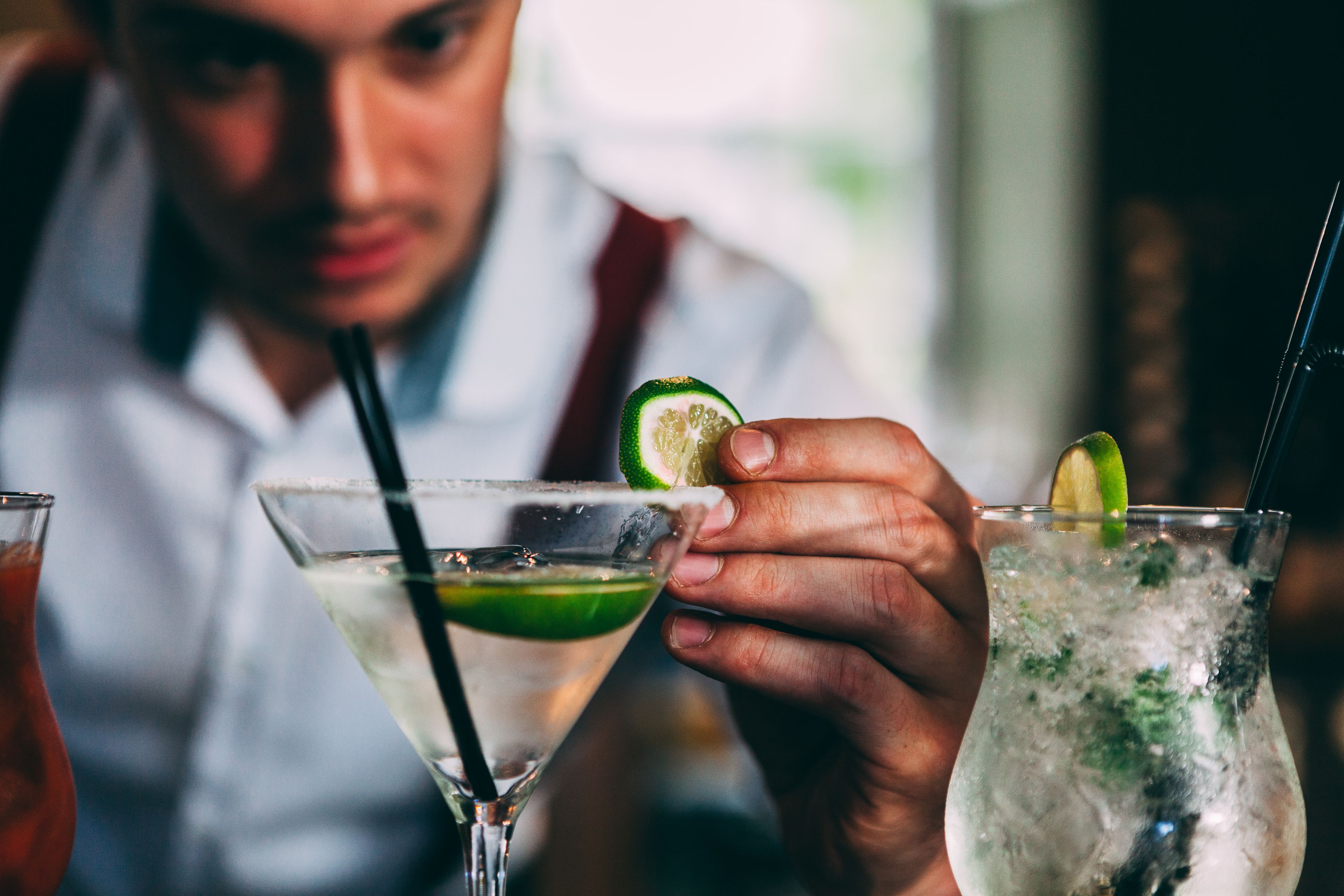 A person holding a cocktail glass with a lime wedge.