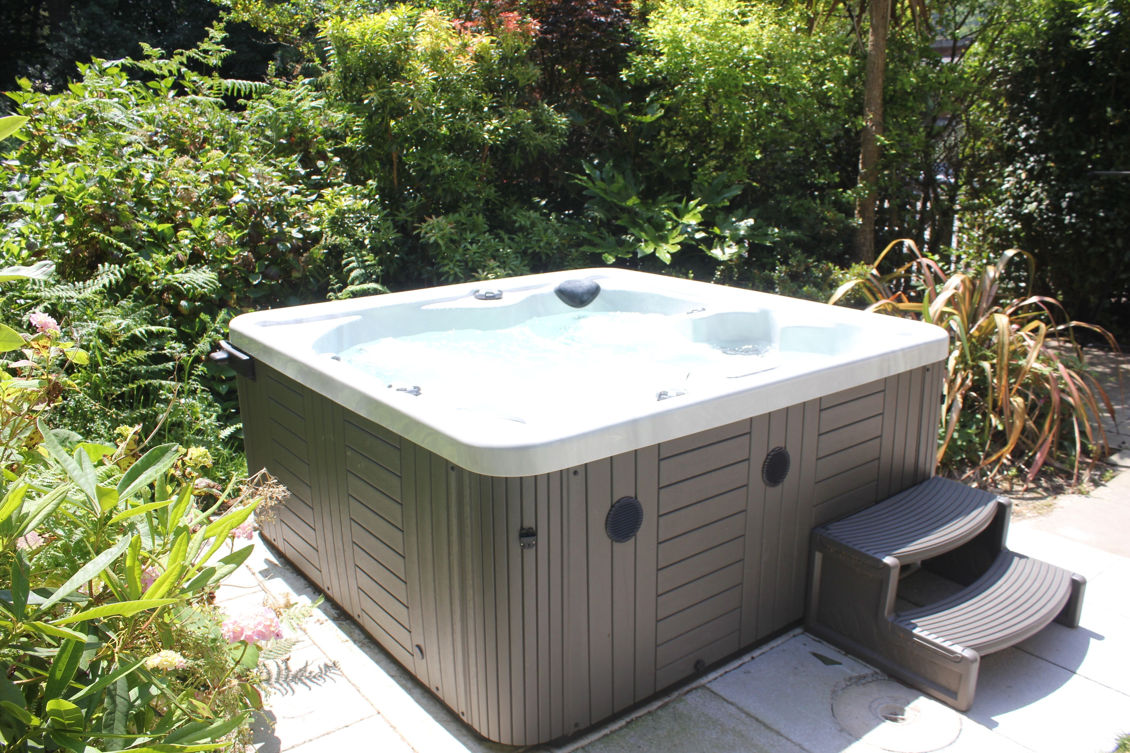 Un jacuzzi al aire libre con una terraza de madera y escalones que dan acceso a él.