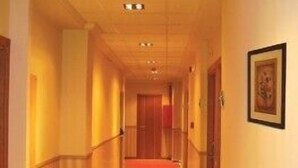 Un couloir d’hôtel avec un tapis rouge, des murs en bois et un tableau encadré accroché au mur.