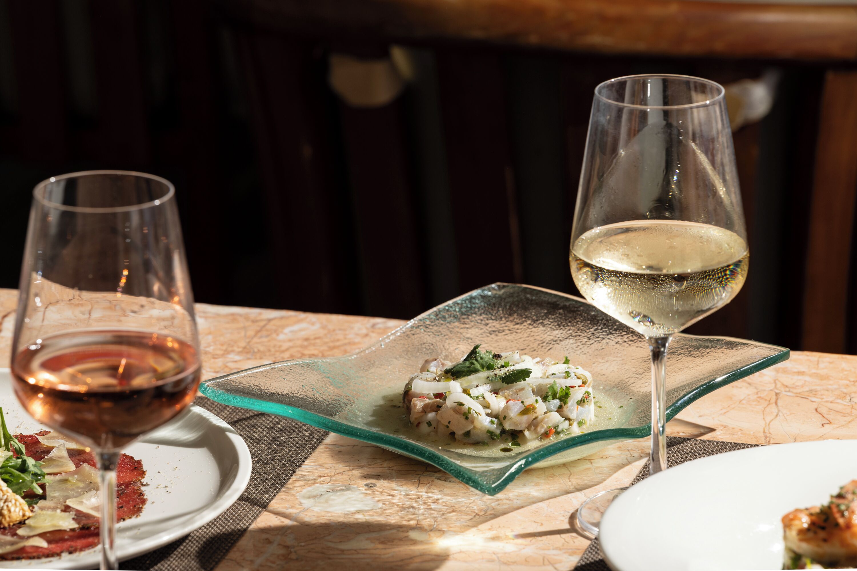 Una mesa de comedor con un plato de comida y dos copas de vino.