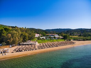 A beach resort with rows of sun loungers and umbrellas, a pool area, and buildings in the background. - Skiathos Princess Resort (Skiathos)