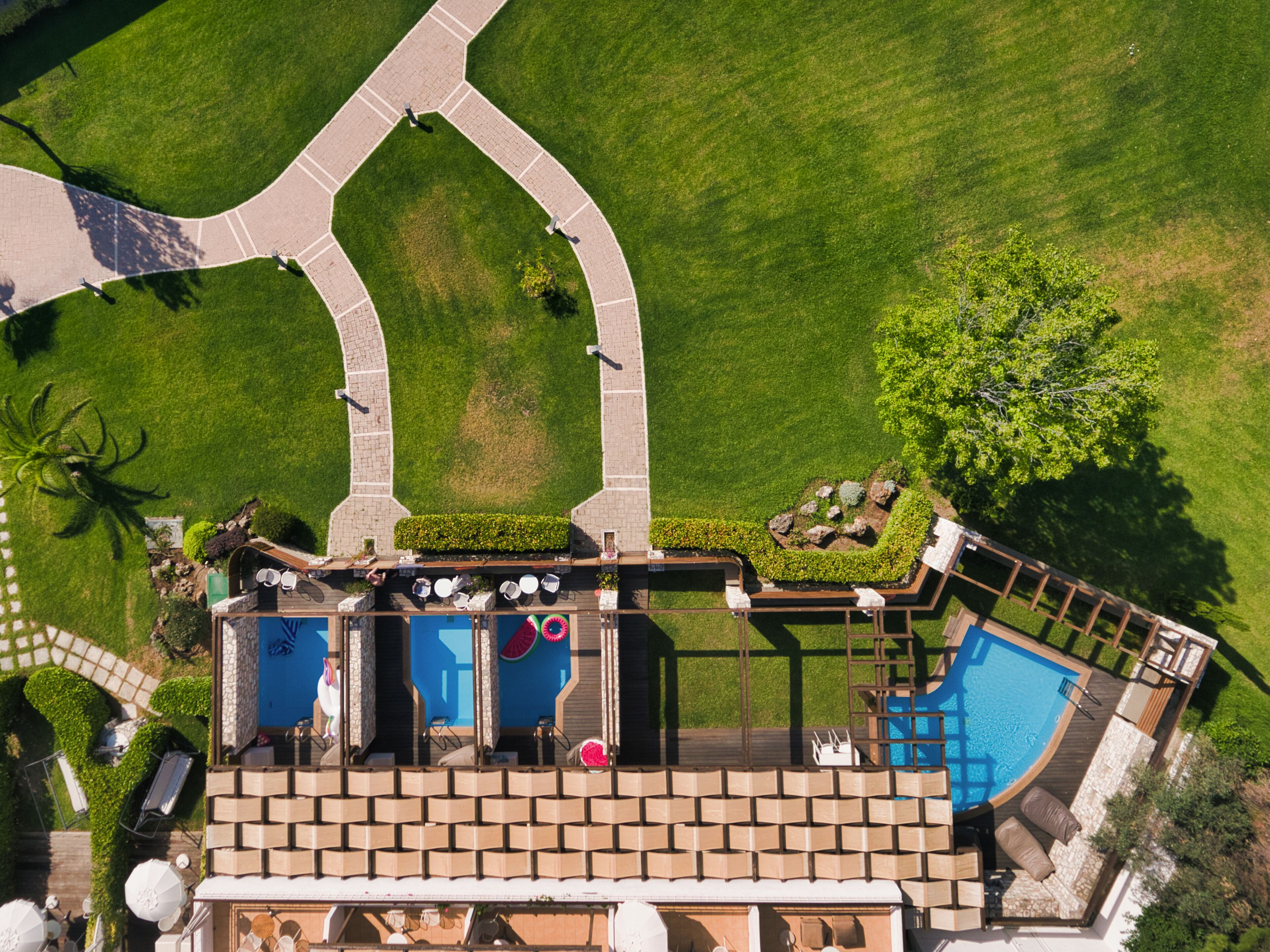 An aerial view of a resort with a swimming pool, outdoor seating, and landscaped areas.