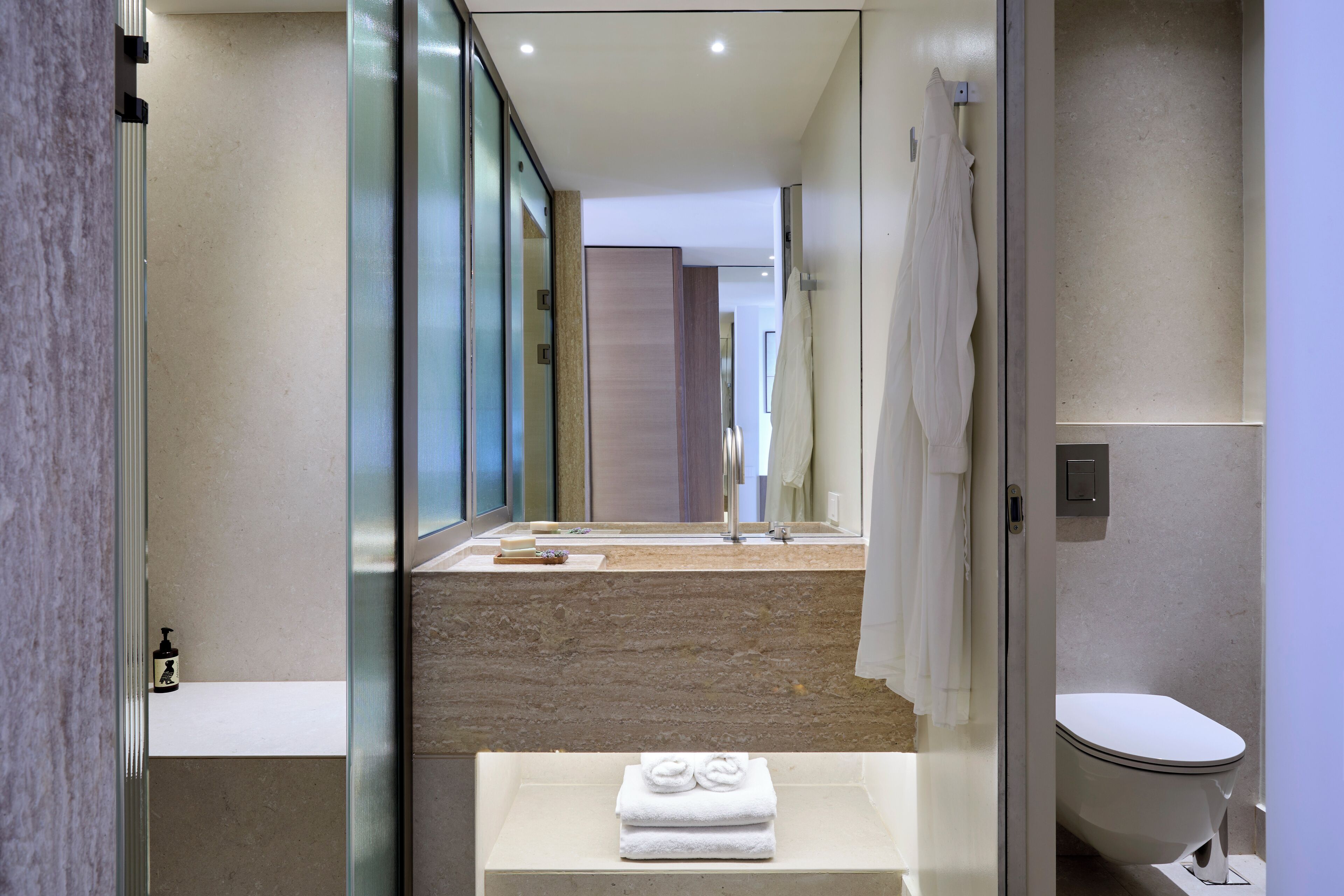 Un baño moderno con cabina de ducha de vidrio, un espejo grande y un lavabo blanco con una toalla.