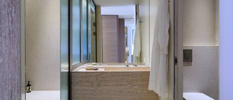 Un baño moderno con cabina de ducha de vidrio, un espejo grande y un lavabo blanco con una toalla.