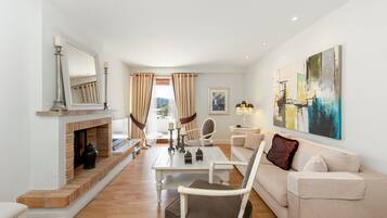 A modern living room with a fireplace, a sofa, a dining table, and a large abstract painting.