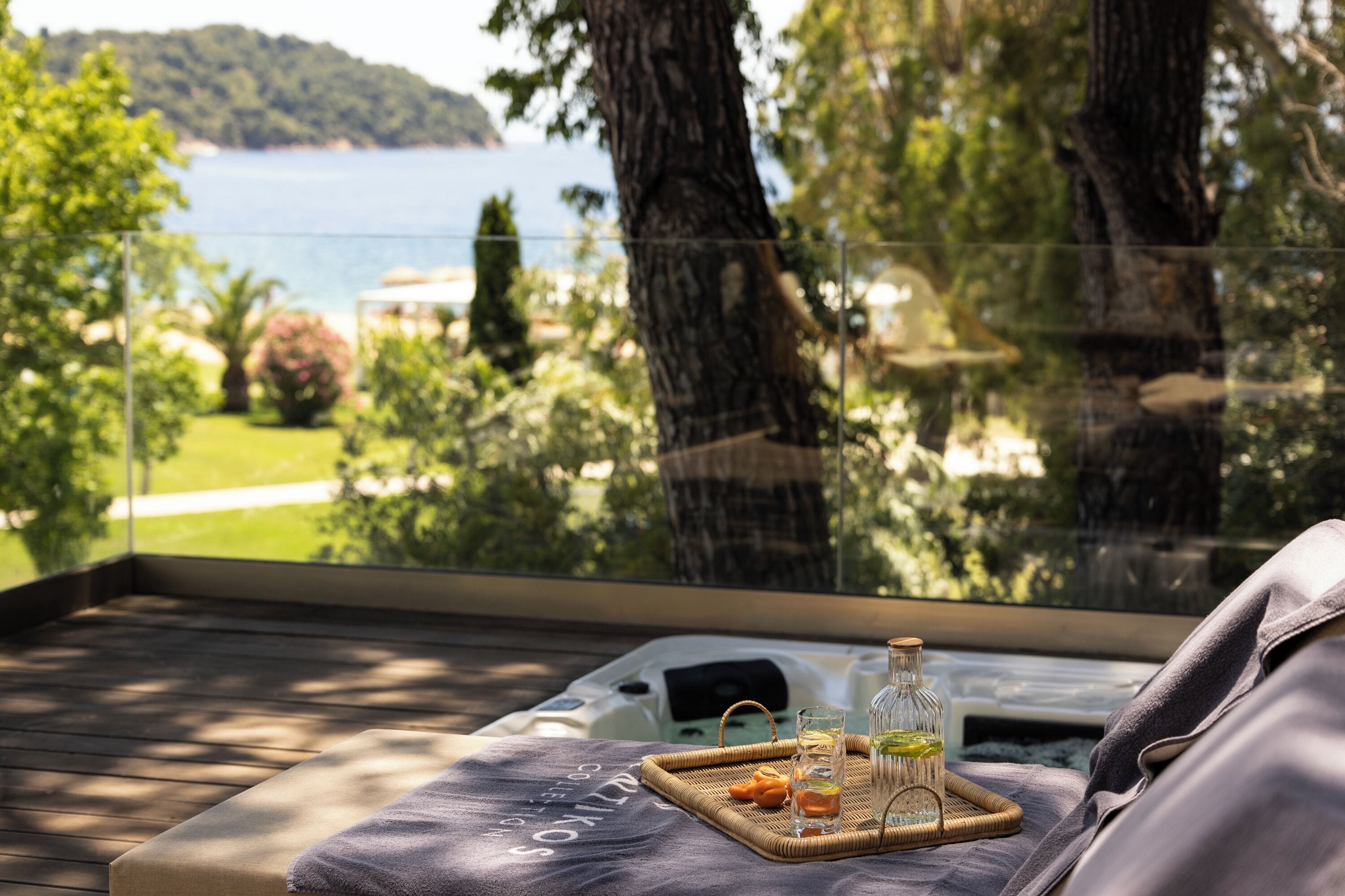 Ein Balkon mit Meerblick, eine Glasflasche, ein Glas und ein Tablett mit Snacks.
