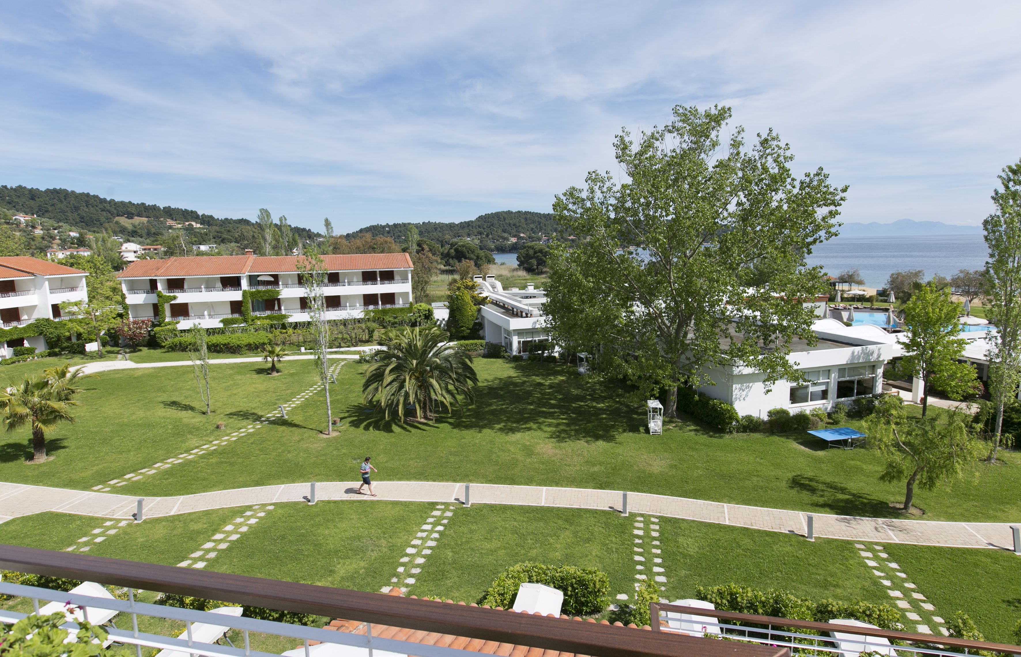 A resort with multiple buildings, a well-maintained lawn, and a view of the sea.
