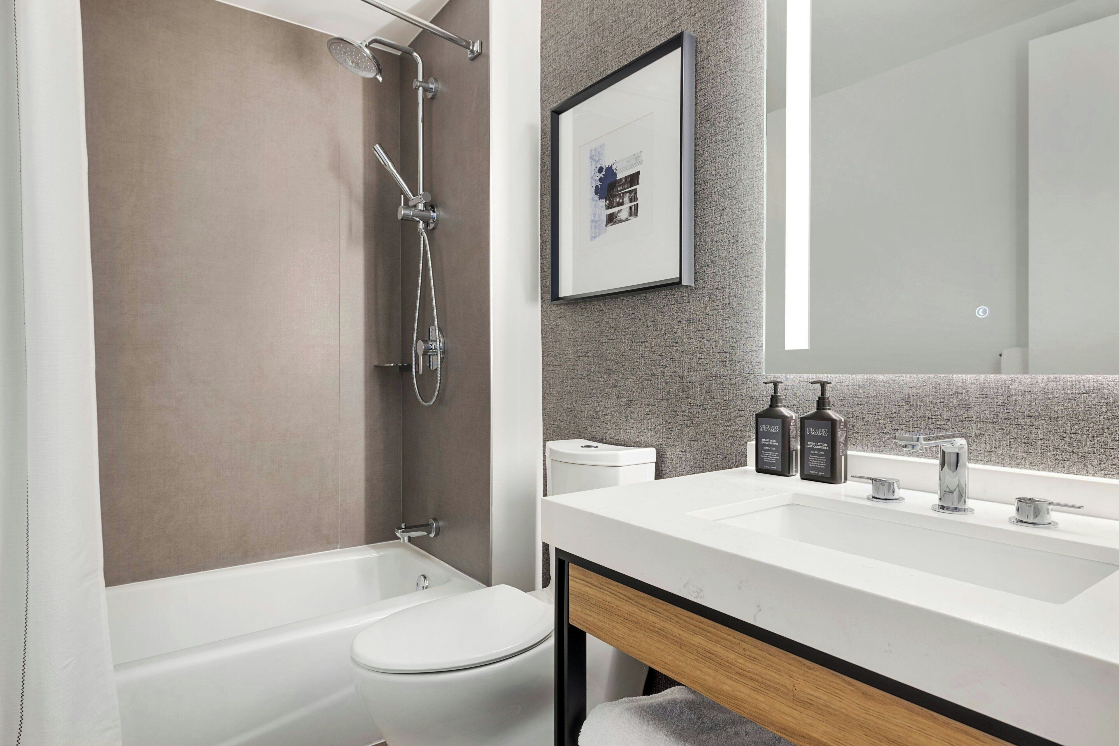 Une salle de bain moderne avec une baignoire, des toilettes et un grand miroir au-dessus du lavabo.