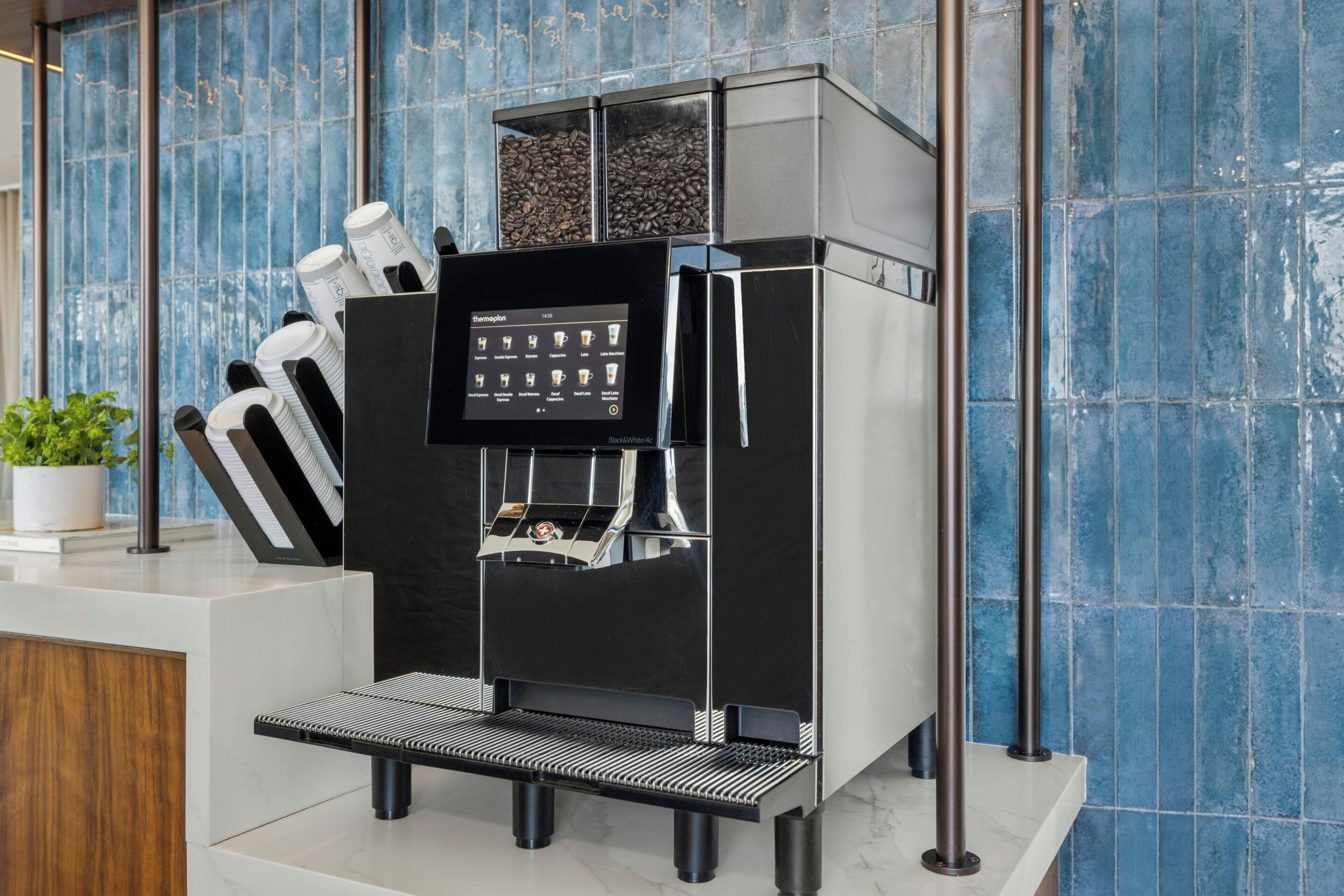 A modern espresso machine with a digital display, coffee cups, and a coffee grinder.