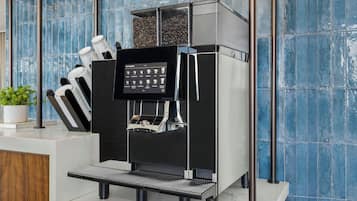 Uma máquina de café expresso moderna com visor digital, xícaras de café e um moedor de café.