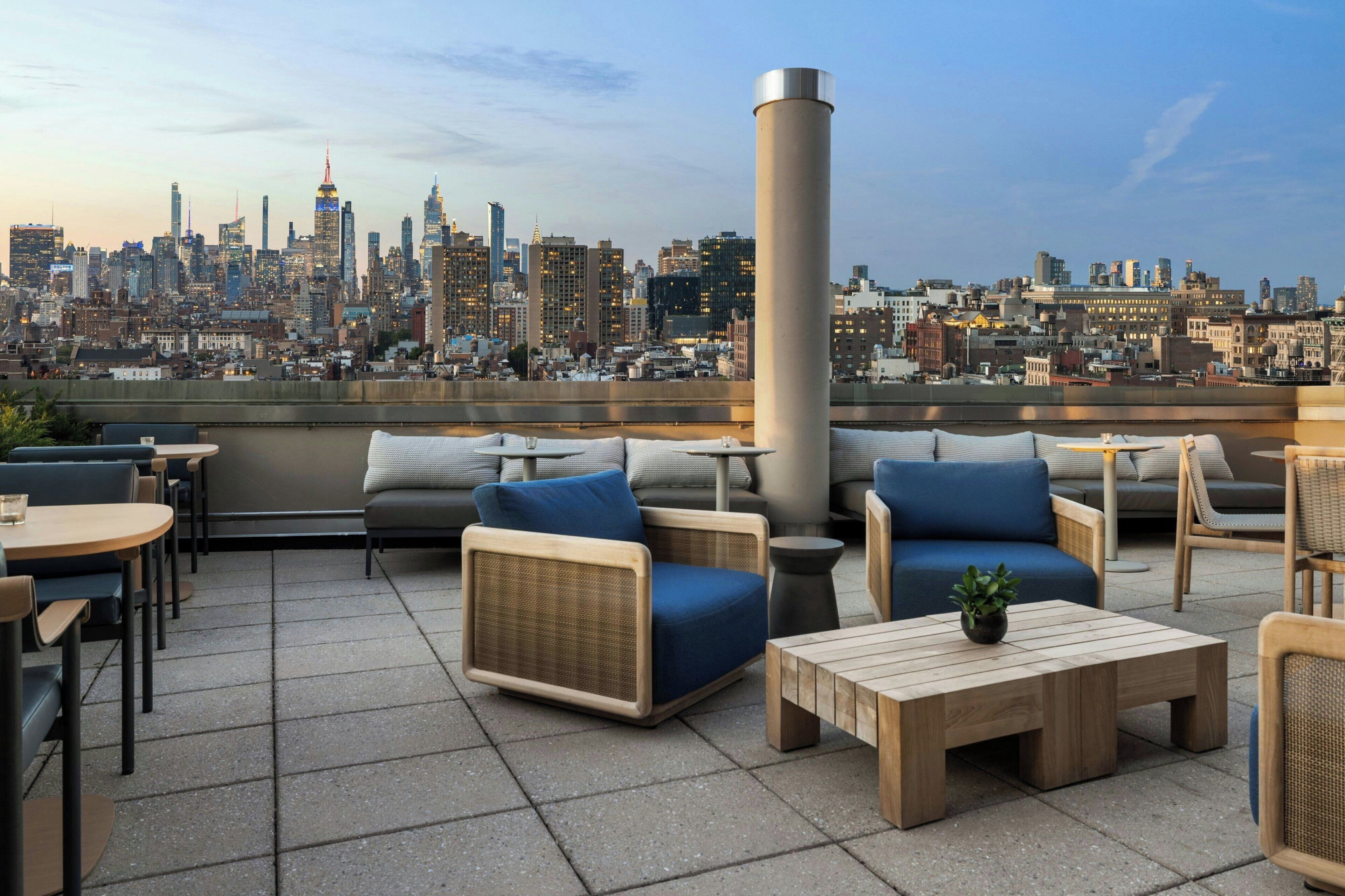 Una terraza en la azotea con asientos al aire libre, vistas al horizonte de la ciudad y una estructura de columna grande.
