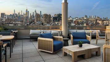 Una terraza en la azotea con asientos al aire libre, vistas al horizonte de la ciudad y una estructura de columna grande.
