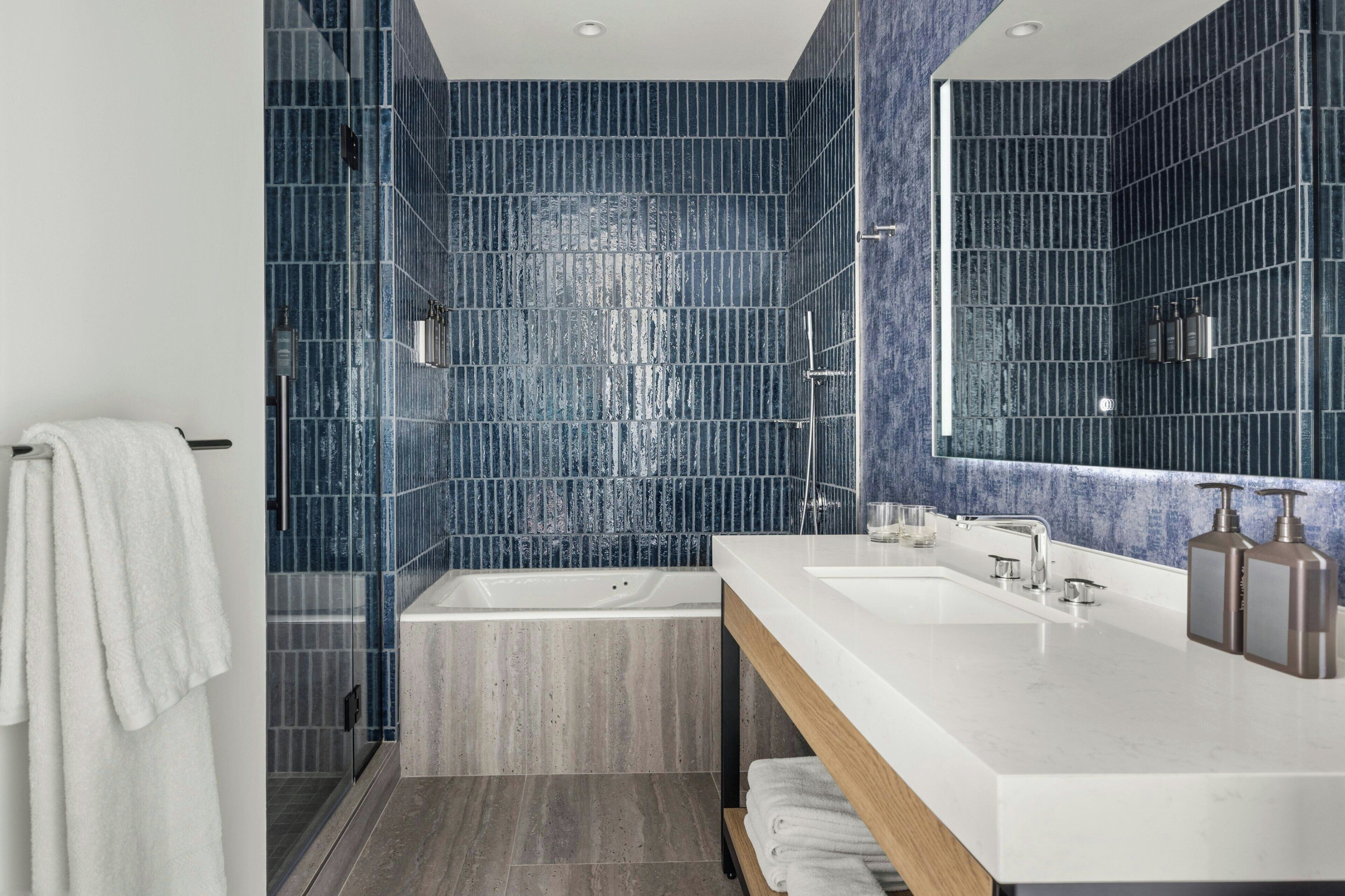 Une salle de bain moderne avec une grande baignoire, un double vasque et un grand miroir.