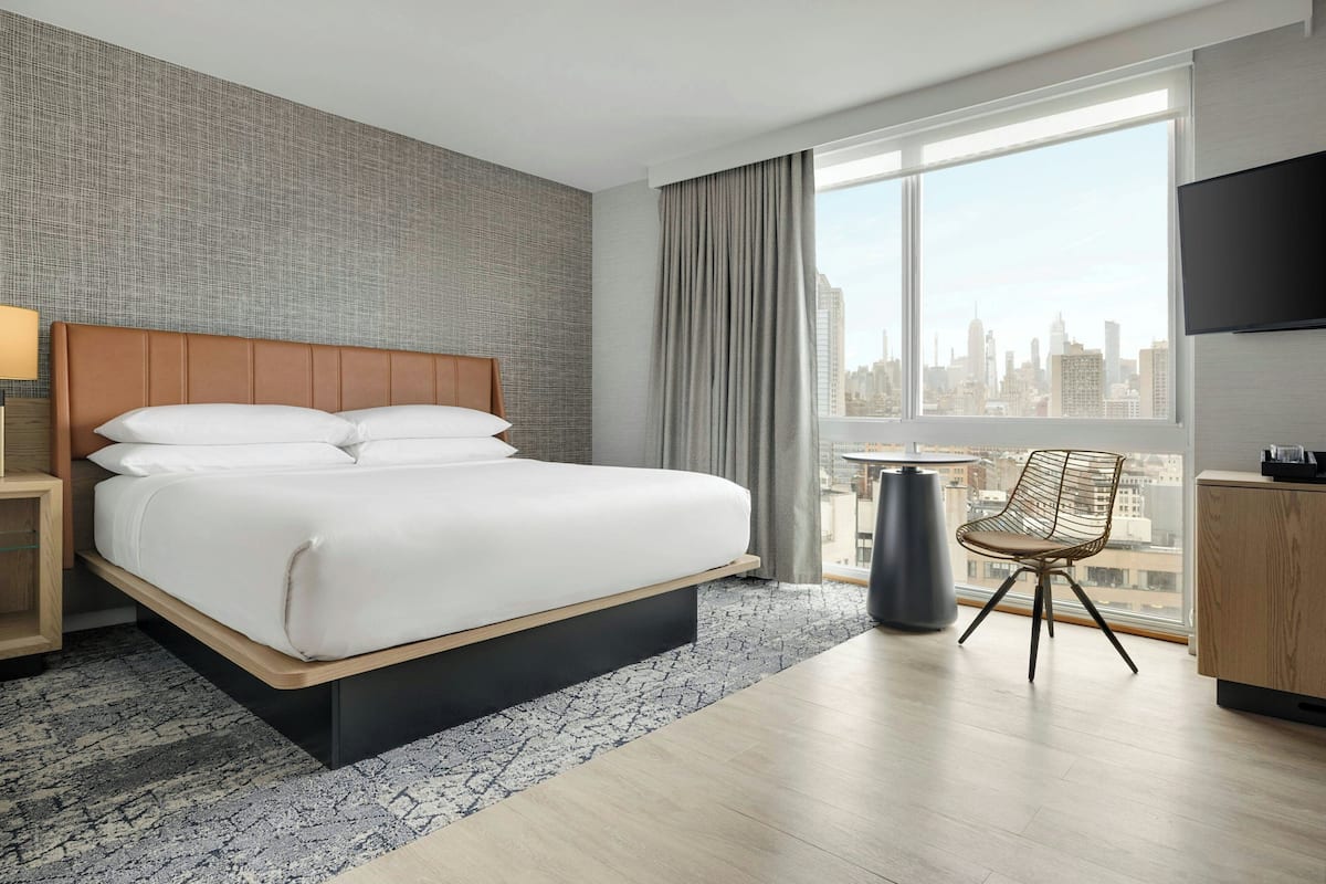 Une chambre d’hôtel avec un grand lit, une chaise, une télévision et une vue sur la ville.