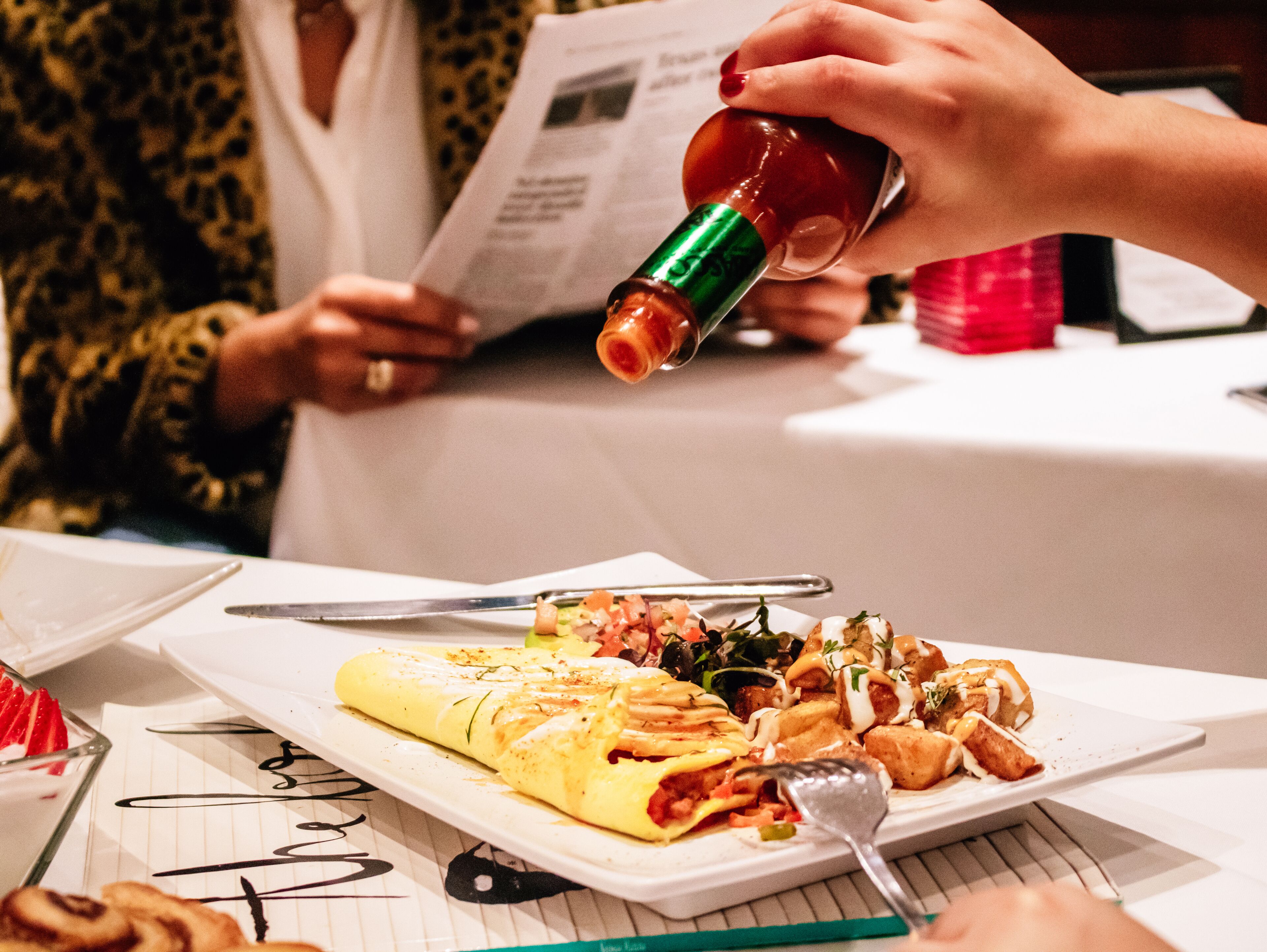 A dining table with a plate of food, a fork, and a bottle.