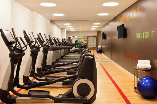 A gym with multiple treadmills lined up against a wall with motivational phrases.