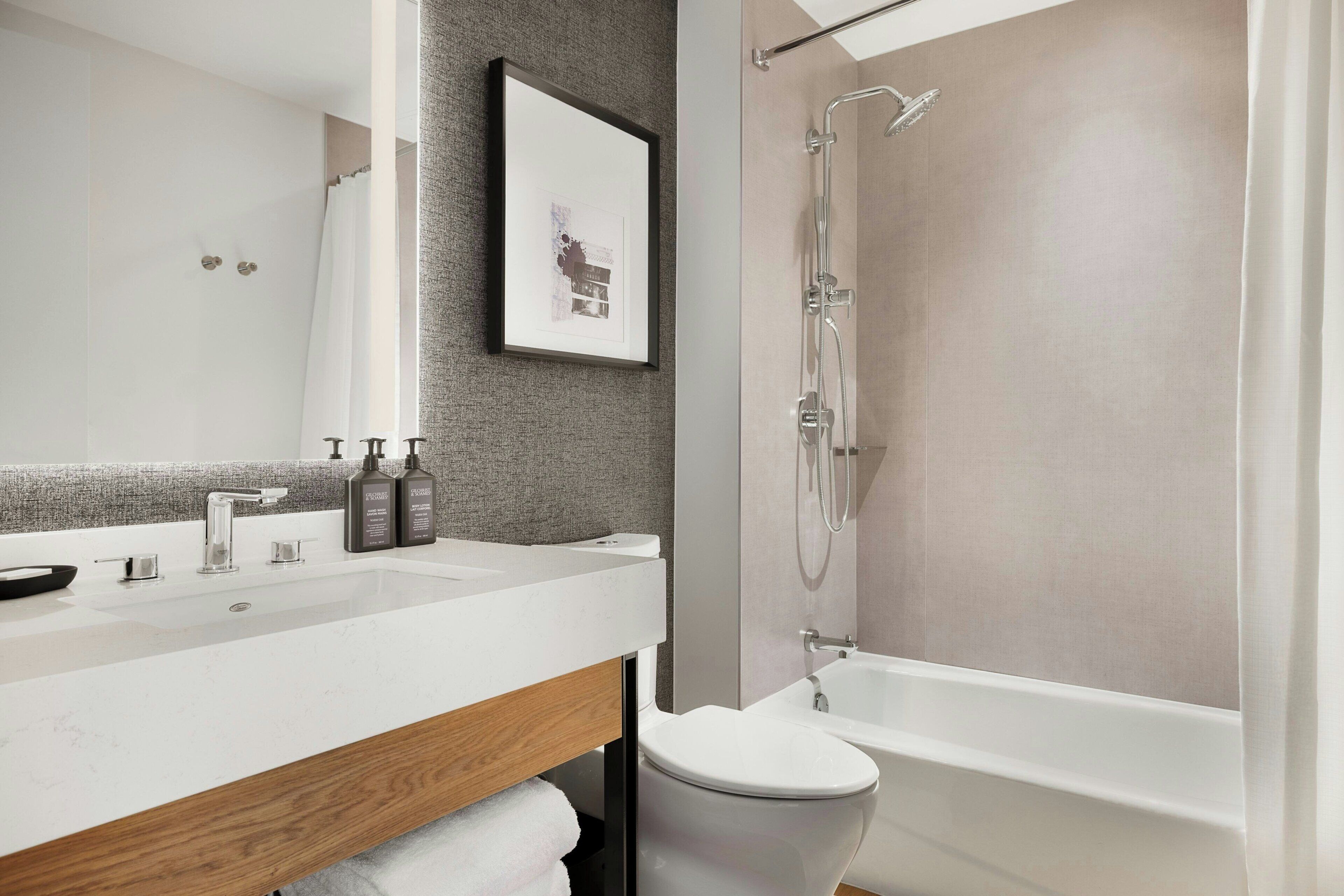 A modern bathroom with a large sink, mirror, and shower.