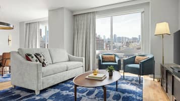 A modern living room with a sofa, armchair, coffee table, and a city view.