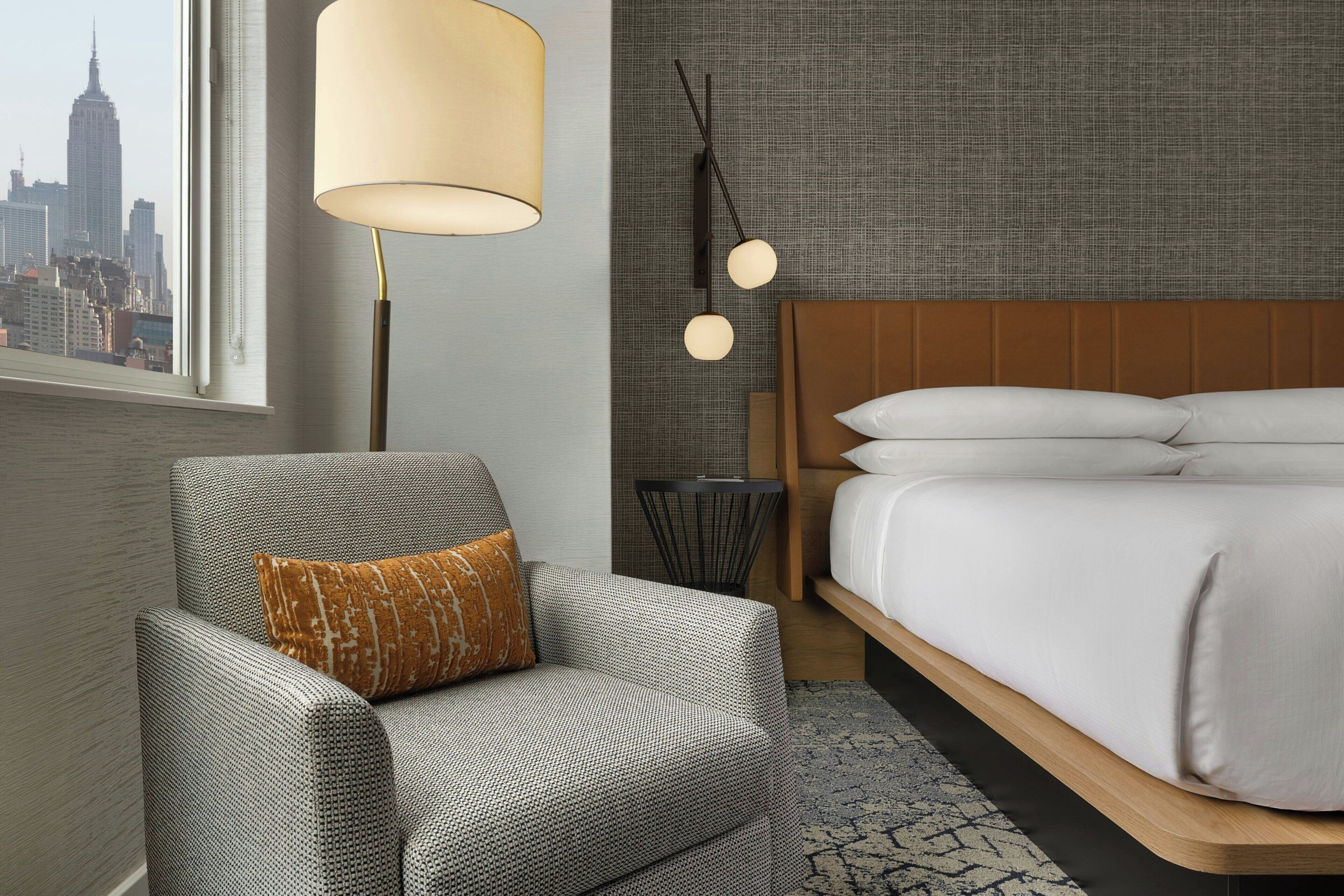 Ein Hotelzimmer mit Blick auf die Stadt, inklusive Sofa, Bett, Lampe und einer Wand mit Struktur.