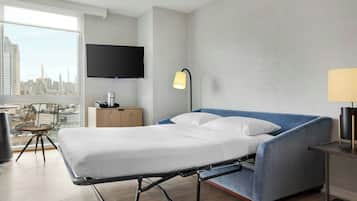 A modern hotel room with a bed, a TV, a lamp, a chair, and a city view.