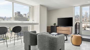 A modern living room with a city view, a flat-screen TV, and a dining area.