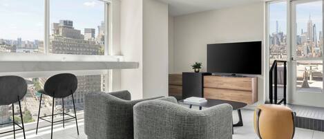 A modern living room with a city view, a flat-screen TV, and a dining area.