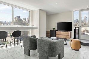 Een moderne woonkamer met uitzicht over de stad, een flatscreentelevisie en een eethoek.