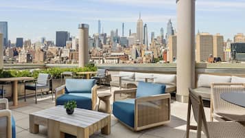 A rooftop terrace with outdoor seating, a city skyline view, and a modern urban environment.