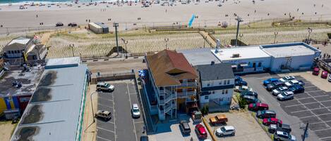 A coastal hotel with a parking lot, beach view, and a boardwalk.