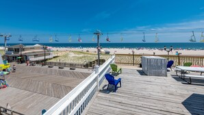 A beachside boardwalk with a wooden deck, beach chairs, and a view of the ocean. - Boardwalk Hotel Charlee & Beach House Rentals (Seaside Heights)