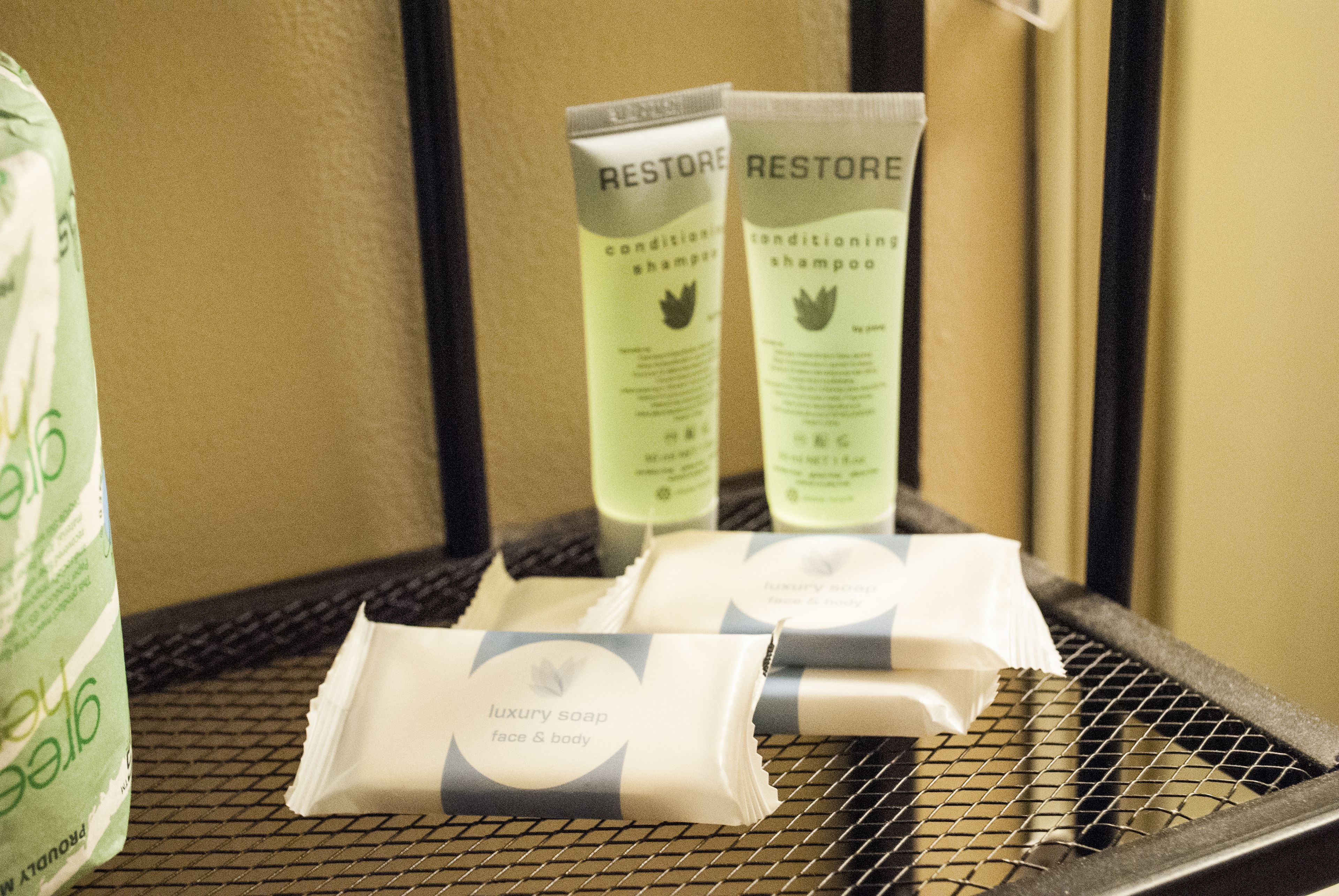 Articles de toilette disposés sur un plateau, notamment un savon de luxe et un shampooing revitalisant de la marque Restore.