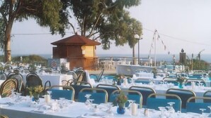 A banquet hall with tables set for a formal event, overlooking a scenic coastal area. - Irinna Hotel (Kefalonia)
