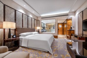 Habitación de hotel con una cama grande, lámparas de noche, escritorio y televisión.