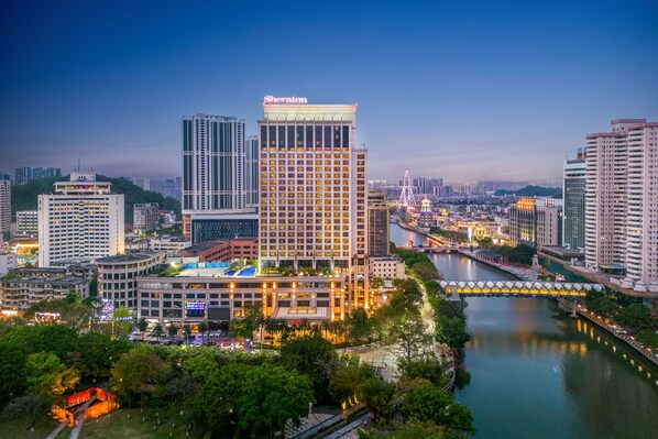 Un hotel Sheraton de diseño moderno, rodeado por un río y otros edificios altos.