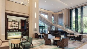A spacious lobby with a bar area, seating arrangements, and a staircase leading to upper floors. - Sheraton Zhongshan Hotel (Zhongshan)