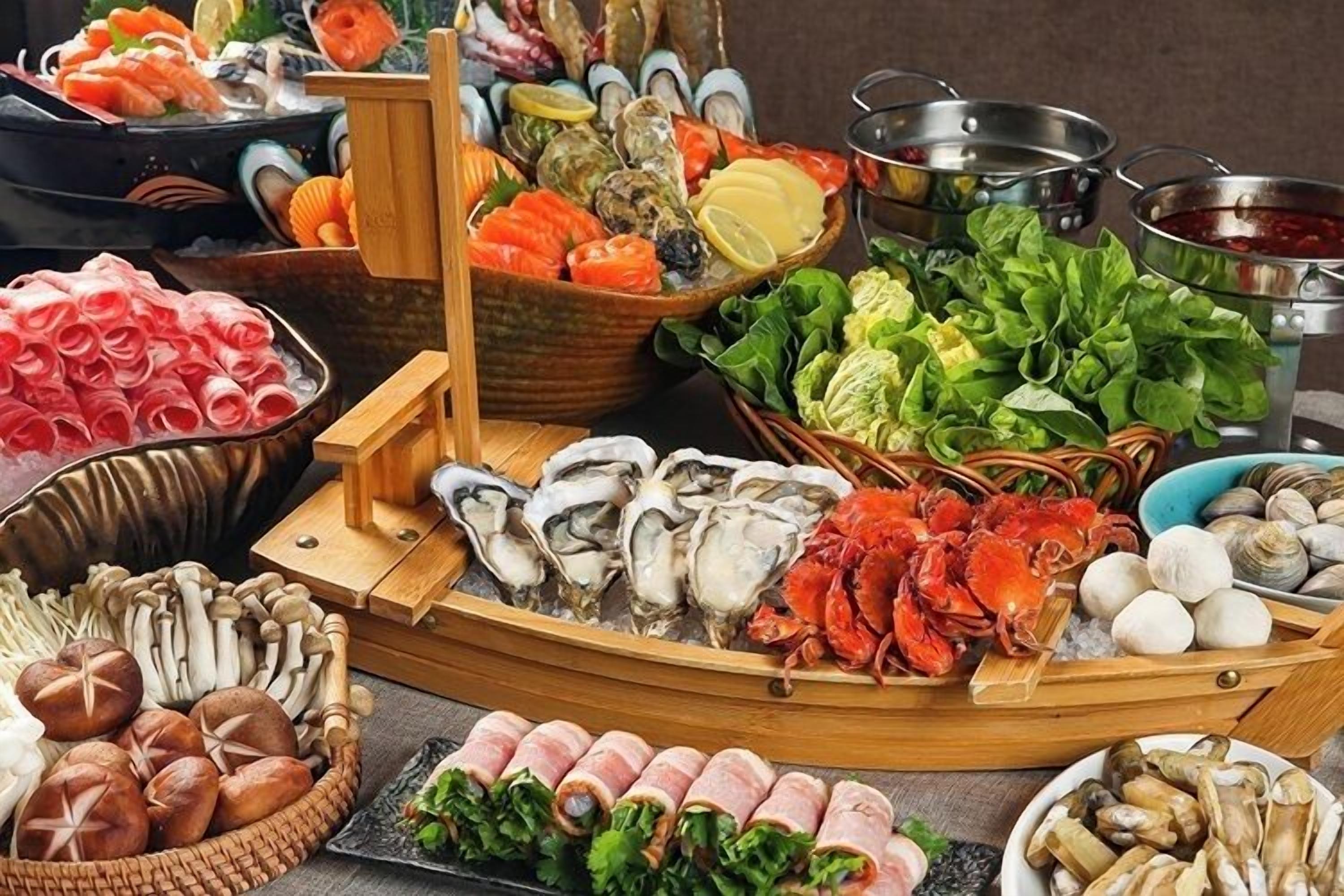 A variety of seafood including oysters, crab, and shrimp, arranged on a wooden boat-like structure.