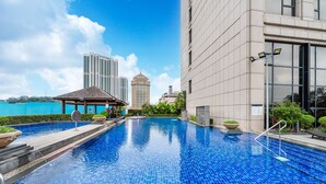 A swimming pool with a tiled blue surface, a gazebo, and a building with large windows. - Sheraton Zhongshan Hotel (Zhongshan)