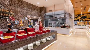 A buffet area with various food items and a kitchen in the background.